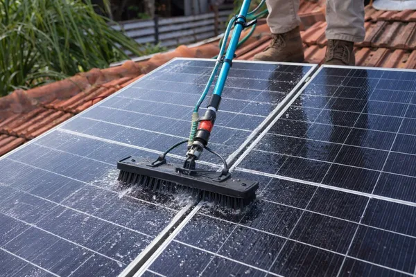 תקריב של מברשת מנקה פאנל סולארי עם מים