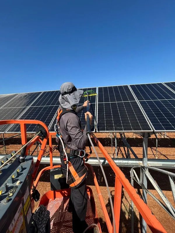 עובד על מנוף מנקה פאנלים סולאריים בחוות סולארית